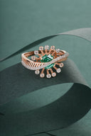 Elegant rose gold ring with green emerald and sparkling diamonds.