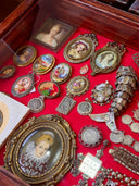 Antique portrait miniatures and jewelry displayed on a bright red velvet surface