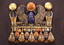 An ancient Egyptian gold pectoral featuring a winged scarab beetle and hanging lotus pendants.