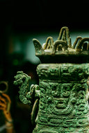 An ancient bronze vessel with intricate relief carvings and a dragon-shaped handle