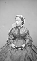 A woman in a striped Victorian dress with a lace headpiece and jewelry