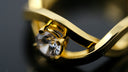 A macro view of a gold ring with a single clear gemstone