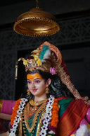 A statue of a Hindu goddess adorned with gold jewelry and floral garlands