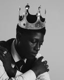 A person wearing a silver crown and a white shirt with a dark tie