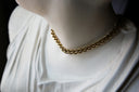 A gold chain necklace around the neck of a white classical statue bust