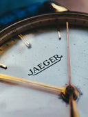 A vintage jaeger watch face with silver dial and gold-tone hands reflecting fine jewelry and art gold craftsmanship.
