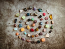 A collection of polished multicolored gemstones arranged in a circle showcasing fine jewelry for art gold jewelry designs