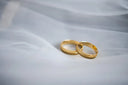 Two interlocking gold wedding bands on white fabric showcasing art gold jewelry and gold jewelry elegance.