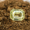 Radiant yellow emerald-cut diamond in soil, rarest luxury gemstone