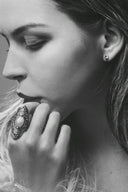 An ornate dark-toned engagement ring with intricate filigree and a central oval pearl in art gold jewelry style.