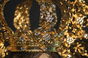 An ornate gold crown with intricate floral filigree and clear gemstones featured in historical crown jewels.