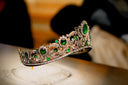 An ornate gold jewelry tiara with vibrant green emeralds and sparkling diamonds showcasing royal jewels.