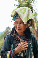 An elderly woman wearing a vibrant green and white headscarf symbolizes jewelry history and royal jewels heritage.