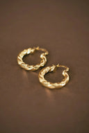 a pair of gold hoop earrings on a brown surface