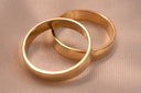 Two interlocking men’s gold rings in 18k gold, one smooth and one textured, ideal as engagement ring options.