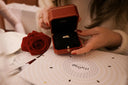 A delicate 18k gold engagement ring in black velvet inside a red Cartier box representing luxury jewelry refinement
