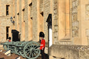 British Royal Guard in red uniform beside historic cannons and royal jewels