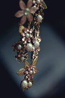 A delicate gold jewelry necklace with pink and clear crystals, white pearls, and intricate leaf designs in 18k gold.