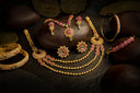 Golden floral necklace with intricate filigree design and pink and green gemstones showcasing handmade gold jewelry quality and gold purity