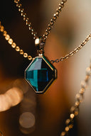 A teal hexagonal gemstone pendant in a gold-tone setting and chain showcasing fine art gold jewelry.
