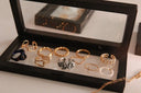 A collection of gold jewelry and silver rings featuring 18k gold twisted bands heart shapes and clear gemstones.