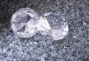 Two transparent faceted gemstones with brilliant cut on crushed glass featured in the size of dreams article at everett jewelry store
