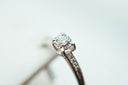 A delicate platinum solitaire engagement ring with round-cut diamond and pavé diamonds in the art gold jewelry collection.