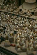 A collection of gold and silver fine jewelry rings with various gemstones displayed on beige velvet stands.