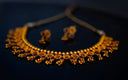 Gold necklace with intricate floral designs and red gemstones crafted in 18k gold for art gold jewelry investment beginners