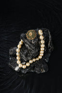 Pearl necklace and brooch on dark rocks