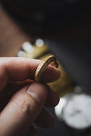 a person holding a gold ring in their hand