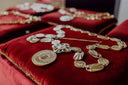 Timeless art gold jewelry: gold coin necklace on red velvet cushion