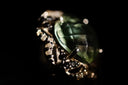 A green faceted gemstone ring set in a dark textured metal band with clear stones epitomizes fine jewelry art gold craftsmanship
