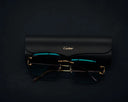 Cartier gold-rimmed glasses with teal lenses on leather case, fine jewelry.