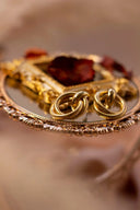 Gold jewelry featuring an ornate 18k gold brooch with a central red gemstone in intricate filigree, highlighting fine jewelry trends