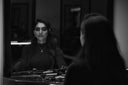 Woman with dark hair admires stunning gemstone jewelry in mirror
