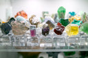 A vibrant yellow cubic mineral specimen displayed on a clear stand highlighting fine jewelry and art gold themes.