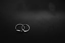 Interlocked minimalist silver wedding bands on dark surface