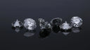 A collection of clear faceted diamonds showcasing rarest gemstones on a reflective black surface for engagement rings.