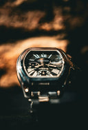 A sleek black Cartier watch with silver hexagonal case and bracelet featuring roman numerals in fine jewelry style.