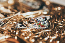 Two interlocking gold rings with beaded design on an ornate silver tray showcasing custom gold fine jewelry.