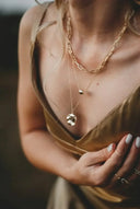 Exquisite 18k gold necklace by Rinaldo Borges with intricate details over beige top