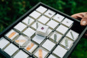A black rectangular display case with clear acrylic boxes showcasing gemstones symbolizing art gold and 18k gold jewelry meanings