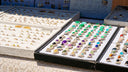 A collection of fine jewelry gemstone rings with silver bands in black trays revealing hidden jewelry compartments.