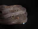 A delicate gold jewelry chain necklace with a teardrop-shaped blue opal pendant in art gold jewelry style.