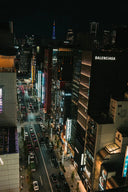 A brightly lit balenciaga store sign in white lettering on a dark facade highlighting luxury jewelry brands piaget and boucheron