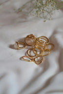 A collection of gold jewelry featuring 18k gold wedding bands with various designs including a pink opal ring.