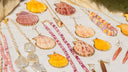 A collection of fine gold jewelry featuring seashell-themed 18k gold chains with pink and orange shell pendants.