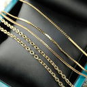 18k gold box chain and rope chain collection on dark surface