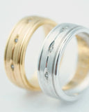 Two wedding rings, one gold and one silver, each set with small diamonds.